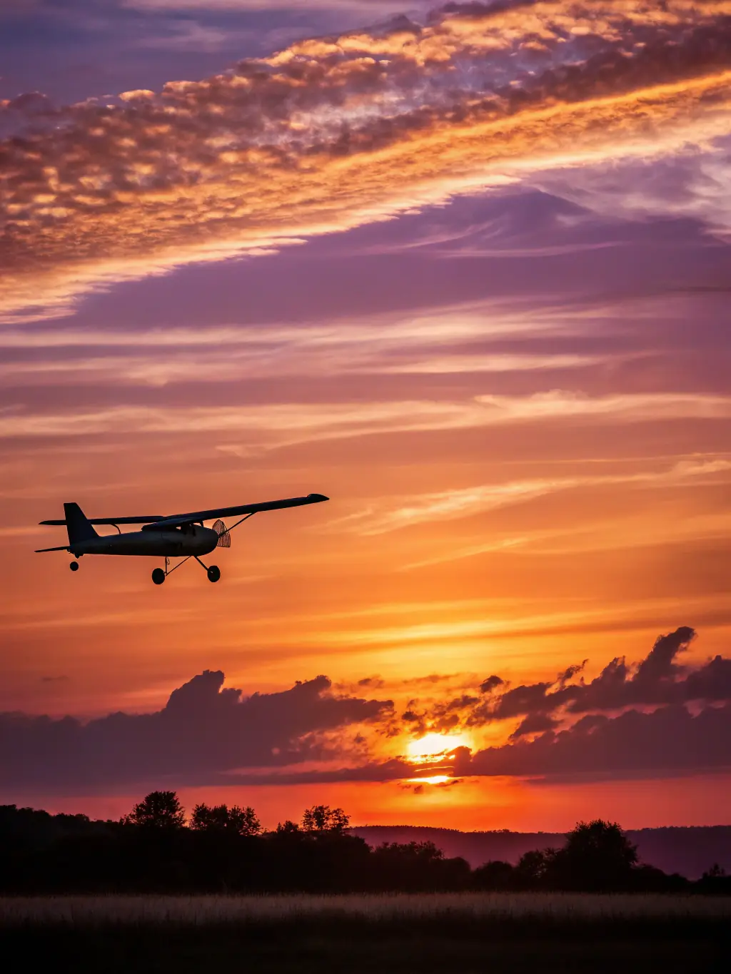 An image of hang gliders preparing for takeoff at sunset, with silhouettes of pilots against the orange sky, emphasizing the adventurous spirit of hang gliding and the beauty of the natural landscape.